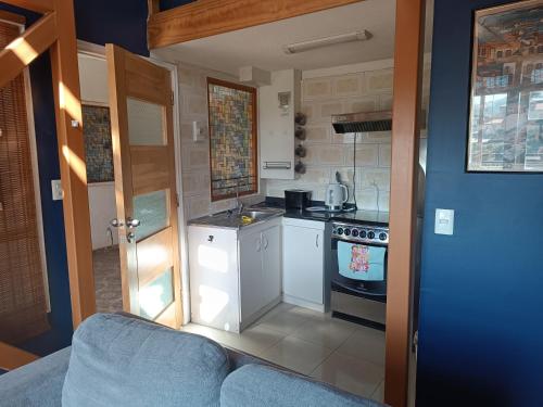 a small kitchen with a stove and a blue couch at Apart Hotel Jagui Haus Departamentos tipo Loft y Hermosa Terraza con vista al Mar in Valparaíso