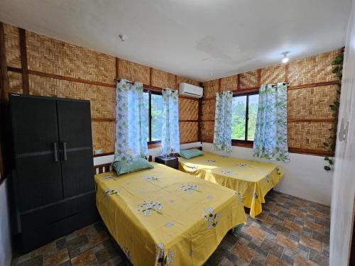 a room with two beds and two windows at Siquijor Cottage Lynn with Solar System in Maria