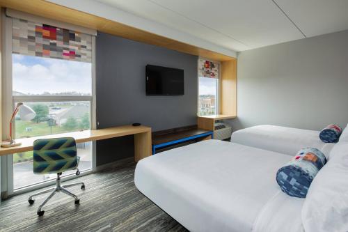 a hotel room with two beds and a desk at Aloft Louisville East in Louisville