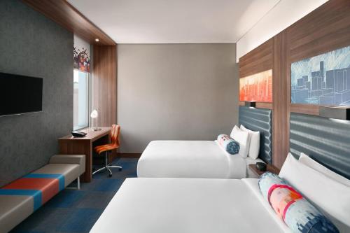 a hotel room with two beds and a desk at Aloft Dhahran Hotel in Al Khobar