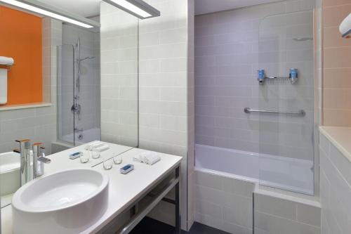 a white bathroom with a sink and a shower at Aloft Dhahran Hotel in Al Khobar