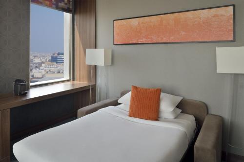 a bed in a hotel room with a window at Aloft Dhahran Hotel in Al Khobar