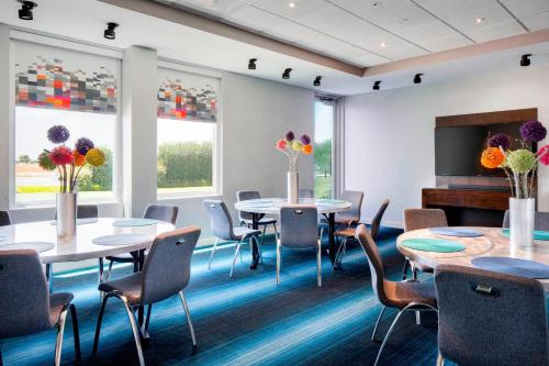 a conference room with tables and chairs and windows at Aloft Hotel Las Colinas in Irving