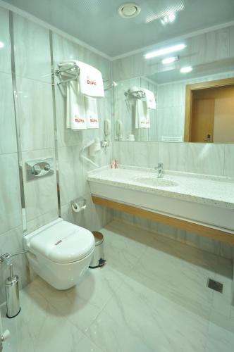a white bathroom with a toilet and a sink at Bupa Hotel in Kayseri