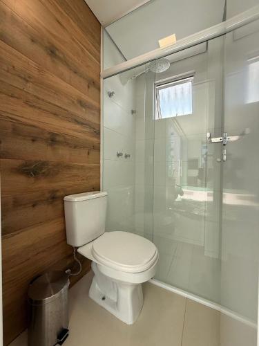 a bathroom with a toilet and a glass shower at QE01- Studio| Jacuzzi Aquecida| Piscina| Churrasq. in Cabeçudas