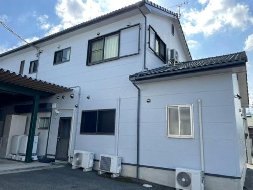 a white house with two chairs in front of it at 合同会社ゲストハウス縁 in Saijo