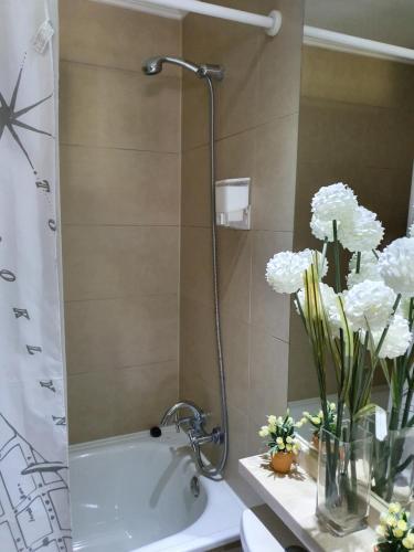 a bathroom with a shower with white flowers in a vase at Departamento con AC Ñuñoa in Santiago