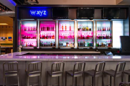 a bar with stools in front of a bar with alcohol bottles at Aloft Lexington in Lexington
