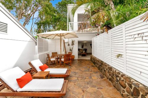 an outdoor patio with chairs and an umbrella at The Reef House Adults Retreat - Enjoy 28 Complimentary Inclusions in Palm Cove