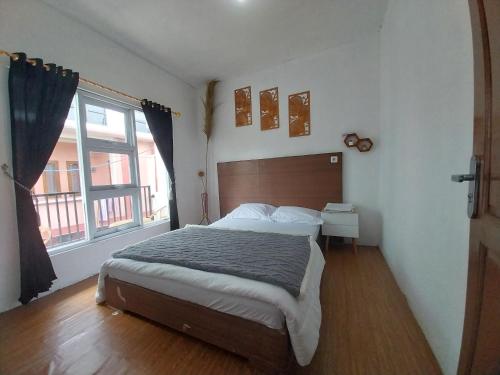 a bedroom with a bed and a large window at Villa kumudini's in Dieng