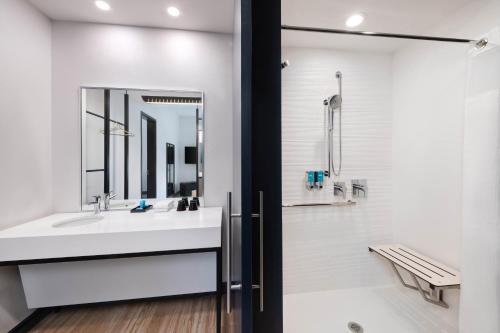 a white bathroom with a sink and a mirror at Aloft Cincinnati West Chester in West Chester