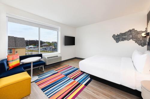 a bedroom with a bed and a desk and a window at Aloft Cincinnati West Chester in West Chester