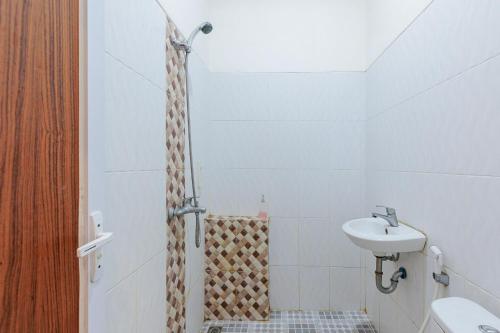 a bathroom with a shower with a sink and a toilet at Urbanview Hotel Tritia Lampung By RedDoorz in Kedaton