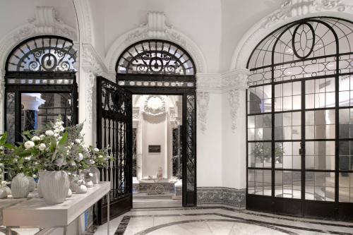 a lobby with two large glass doors and flowers at Hotel Palacio del Retiro, Autograph Collection in Madrid