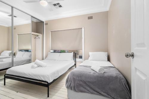a bedroom with two beds and a mirror at Lakeview Retreat on the Esplanade in Warners Bay