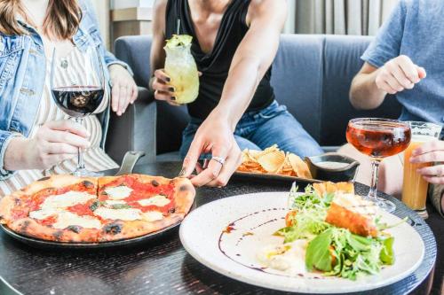a group of people sitting around a table with a pizza at Renaissance Boston Seaport District in Boston