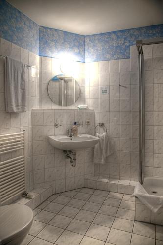 ein weißes Badezimmer mit Waschbecken und Dusche in der Unterkunft Wincent Hotel GmbH in Sinsheim
