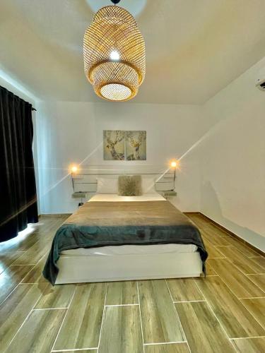 a bedroom with a large bed and a chandelier at Bright Bayahibe condo with pool & beach in Bayahibe