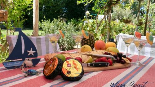 a table with a plate of food and wine glasses at The Inn Between By Wine Coast Holidays in Port Willunga