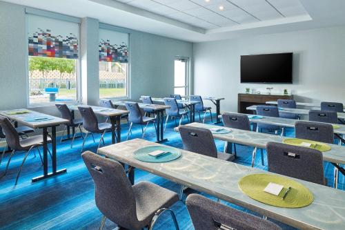 a room with tables and chairs and a flat screen tv at Aloft Hotel Plano in Plano