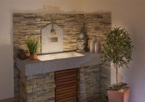 a stone fireplace in a room with a sink at Interest Vitalhotel in Oberstaufen