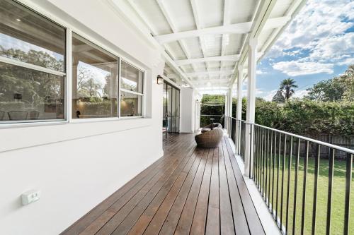 an outdoor deck with a white pergola and windows at Stylish 6BR Strathfield House Tennis & Fun Games in Sydney