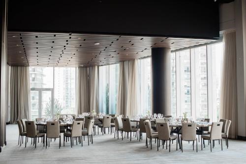 a dining room with tables and chairs and large windows at the DOUGLAS, Autograph Collection in Vancouver