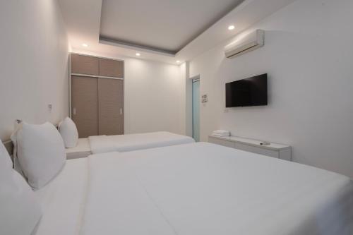 a white bedroom with a bed and a tv at Lakeside House Hanoi in Hanoi