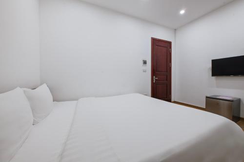 a bedroom with a white bed and a flat screen tv at Lakeside House Hanoi in Hanoi