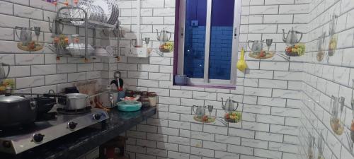 a kitchen with white brick walls and blue windows at Selfie n Studio Homestay in Khānāpāra