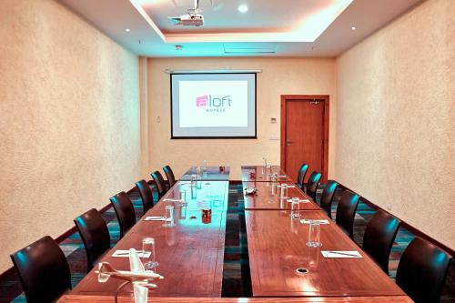 a long table in a room with chairs and a screen at Aloft Bengaluru Whitefield in Bengaluru