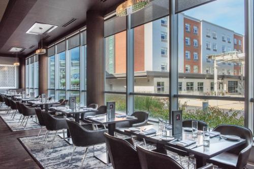 a row of tables and chairs in a room with large windows at Renaissance Boston Patriot Place Hotel in Foxborough
