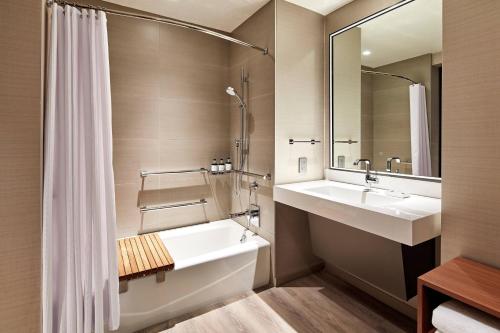 a bathroom with a sink and a tub and a mirror at AC Hotel by Marriott San Jose Santa Clara in Santa Clara
