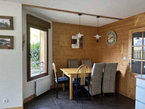une salle à manger avec une table, des chaises et une horloge dans l'établissement Appartement Châtel 3 pièces, 6 pers, proche centre, terrasse, parking - FR-1-676-181, à Châtel