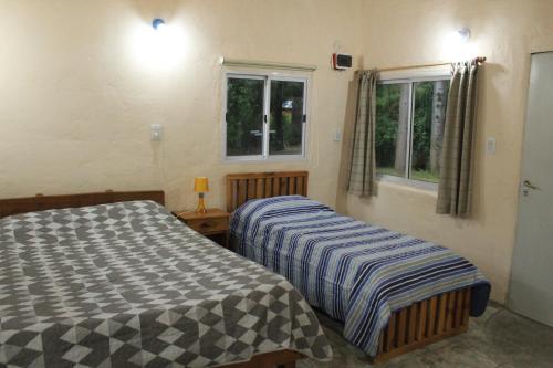 two beds in a room with two windows at Monoambiente Chacra Nadia in Epuyén