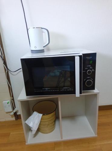 a microwave on a shelf with a cup on top of it at Ohana in Minami Aso