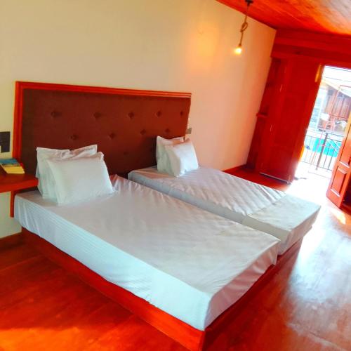 a bedroom with two beds with white sheets and pillows at Thusara Guesthouse in Mirissa