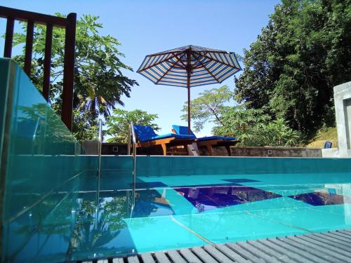a swimming pool with a table and an umbrella at The Moose Weligama in Weligama