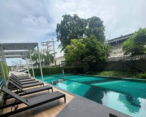 a swimming pool with lounge chairs next to a building at A family room at Lumpini Ville Sukhumvit 101-1 by Pikul in Bangkok