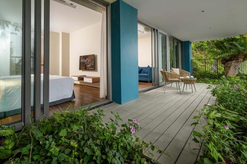 a bedroom with a bed and a balcony with plants at Flamingo Resort Cat Ba in Cat Ba