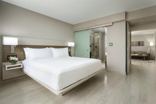 a bedroom with a large white bed and a bathroom at AC Hotel by Marriott San Juan Condado in San Juan