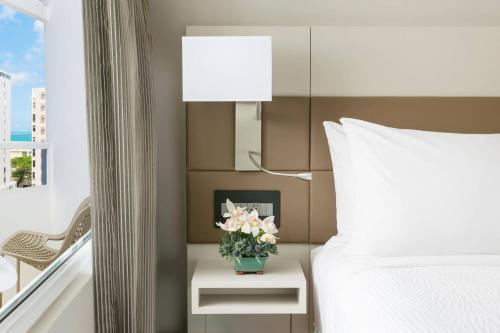 a bedroom with a bed and a vase of flowers on a table at AC Hotel by Marriott San Juan Condado in San Juan