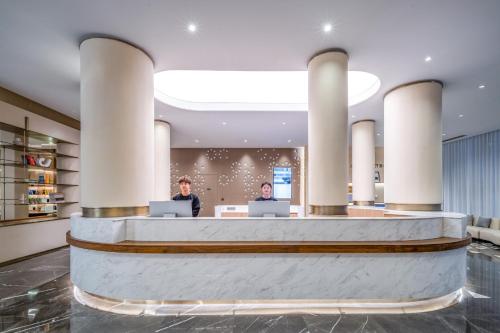 two people sitting at a reception desk in a lobby at Atour Hotel Panzhihua East District Jinhai Century City in Panzhihua