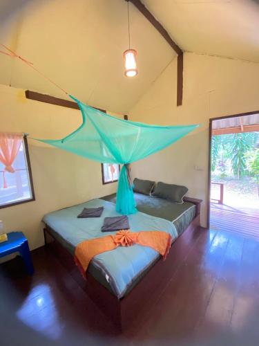 a bedroom with a bed with a mosquito net on it at Eco Bungalow in Ko Phayam