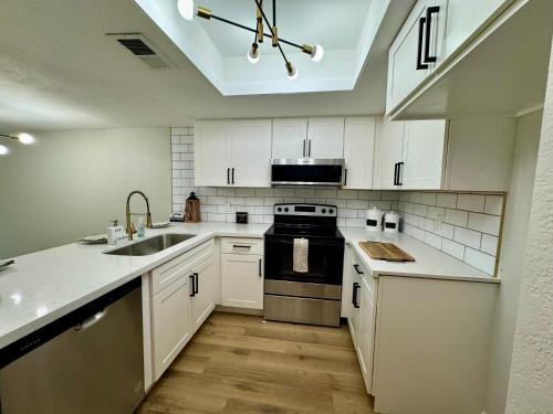 a kitchen with white cabinets and a sink and a stove at beautifully renovated townhouse in Tempe