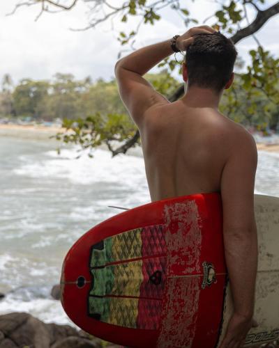 a man standing on the beach holding a surfboard at Beacon By The Bay Villas and Suites by the Clarks in Matara