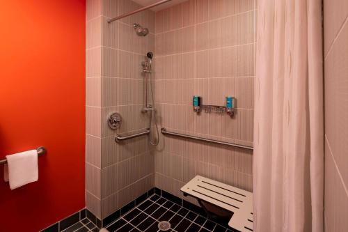 a shower with a bench in a bathroom at Aloft Birmingham Soho Square in Homewood