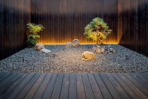 a small tree in a garden with a wooden deck at Matsunoma Machiya House in Kanazawa