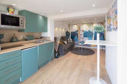 une cuisine avec des armoires bleues et un salon dans l'établissement 2 Pièces terrasse Jacuzzi privatif dans villa à 5 minutes de Sophia Antipolis, à Valbonne