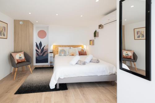 une chambre avec un lit blanc et un miroir dans l'établissement 2 Pièces terrasse Jacuzzi privatif dans villa à 5 minutes de Sophia Antipolis, à Valbonne